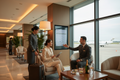 Businessperson in an upscale airport lounge being assisted by a travel concierge, soft warm lighting, professional and aspirational lifestyle photo