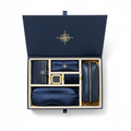 Premium travel gift set in navy and gold magnetic closure box open showing wallet, toiletry bag, neck pillow, sleep mask and earplugs, luxury flat lay on white background